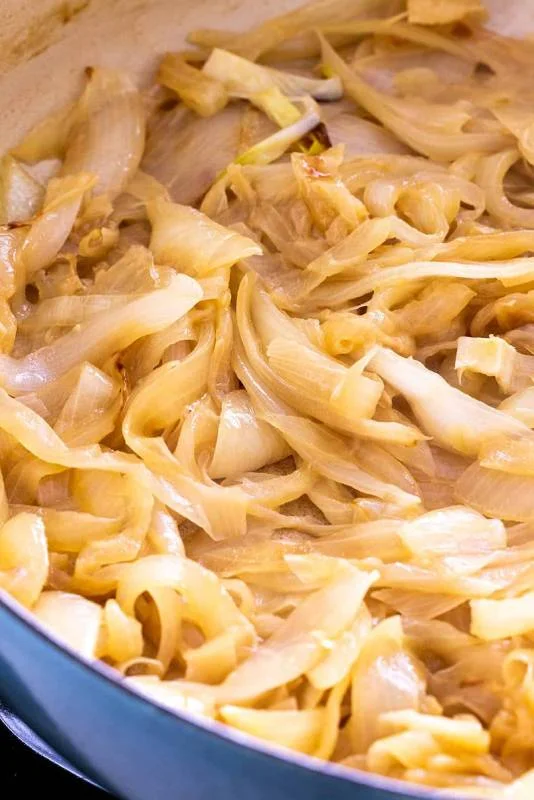 Des tranches d'oignons dans la poêle qui commencent à brunir