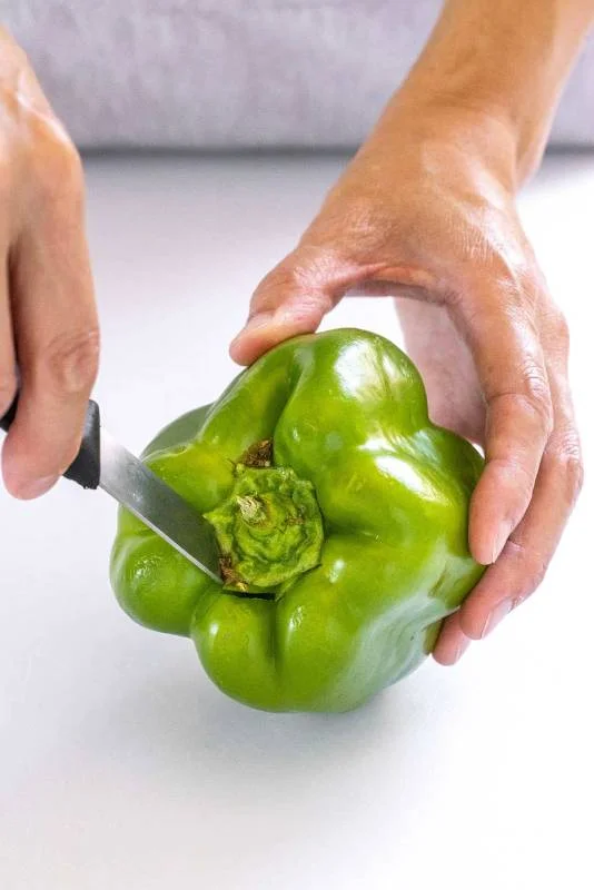 Personne taillant autour de la tige d'un poivron