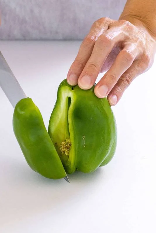 Personne tranchant un morceau d'un poivron vert