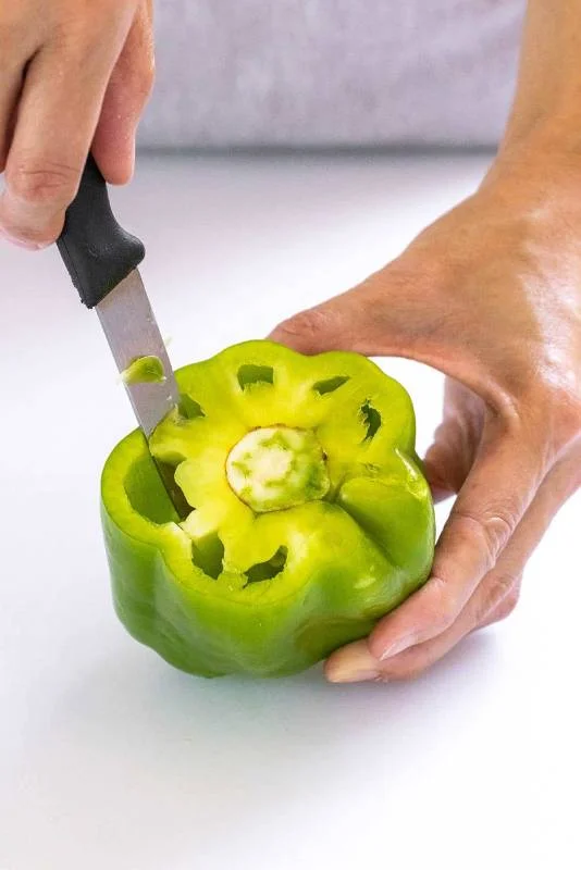 Personne utilisant un couteau d'office pour tailler autour de la membrane d'un poivron