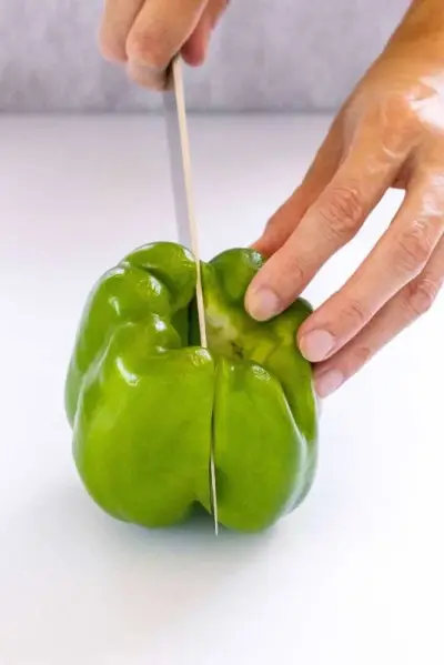 Personne tranchant un poivron vert en deux
