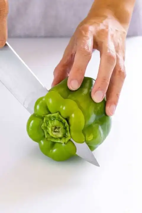 Personne coupant le dessus d'un poivron vert