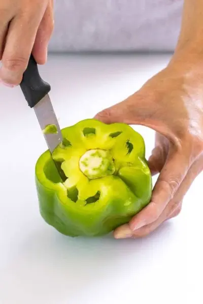 Personne utilisant un couteau d'office pour tailler autour de la membrane d'un poivron
